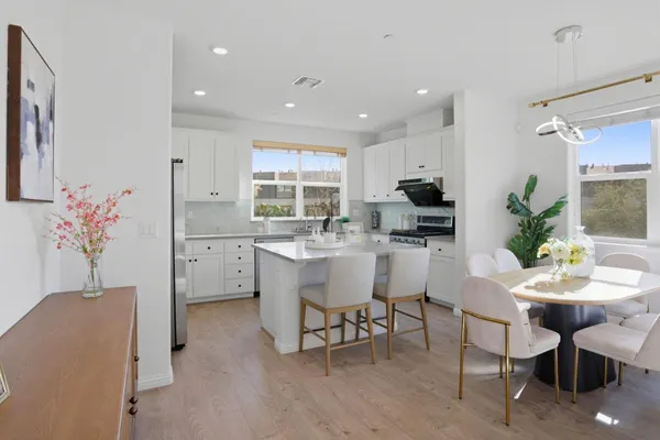 a kitchen with a dining table chairs and refrigerator
