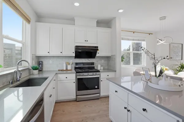 a kitchen with stainless steel appliances granite countertop a sink a stove and cabinets