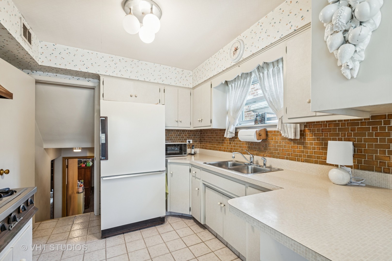 4143 West Devon Avenue Chicago, IL 60646 - Photo 5 of 22 a kitchen with a refrigerator a stove a sink and a cabinets