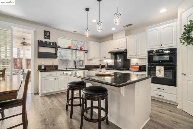 a kitchen with kitchen island granite countertop a sink counter space stainless steel appliances and cabinets