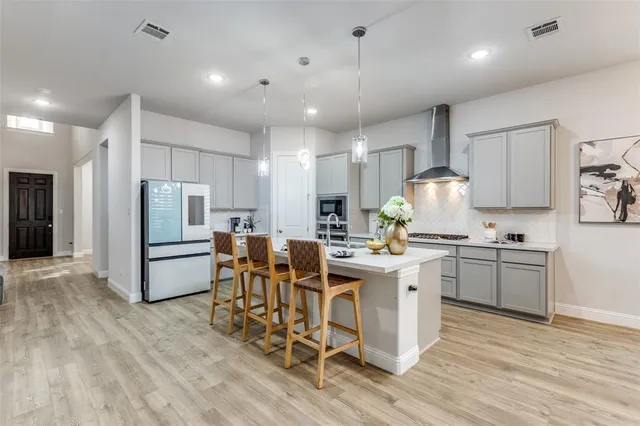 a kitchen with stainless steel appliances kitchen island granite countertop a stove a refrigerator a oven a sink with a dining table and chairs