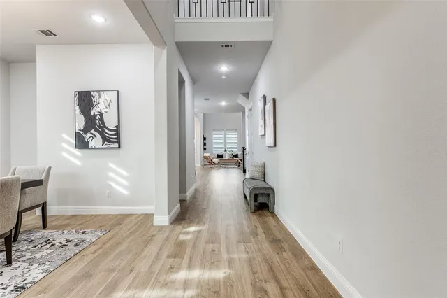 a view of a hallway with wooden floor and a bathroom
