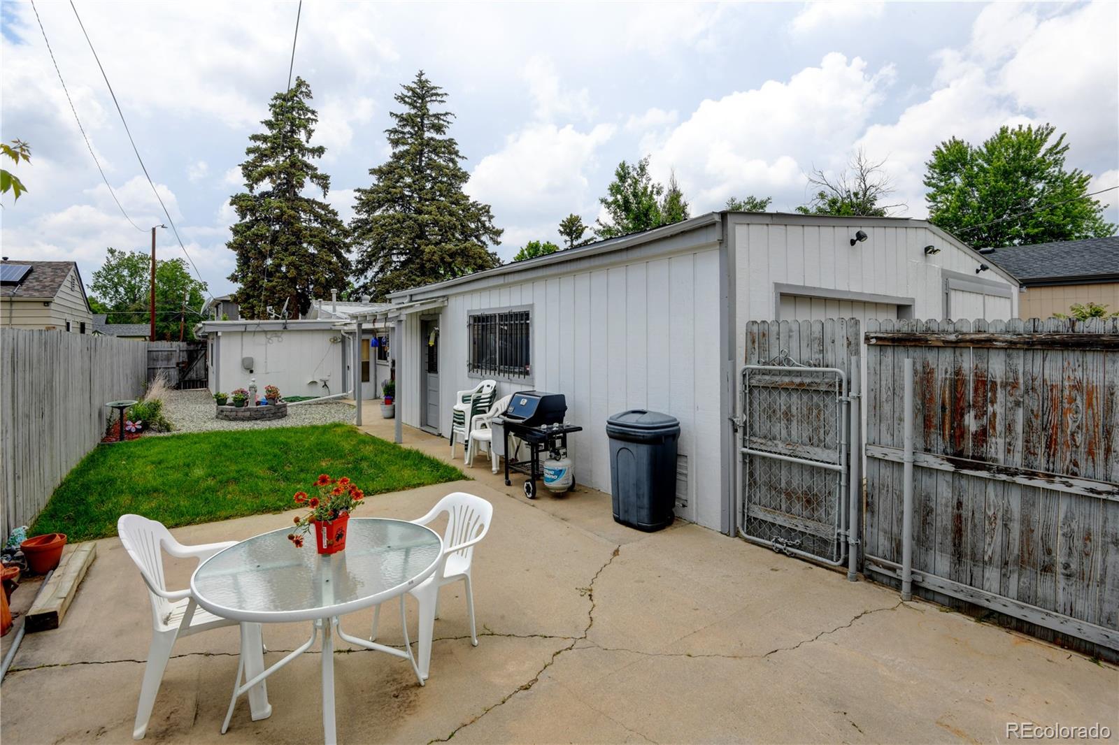 1256 Ulster Street Denver, CO 80220 - Photo 21 of 26 a view of a patio with table and chairs potted plants and a wooden fence