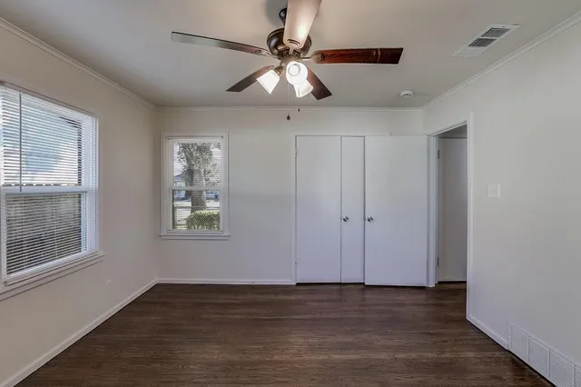 a view of an empty room with window and wooden floor