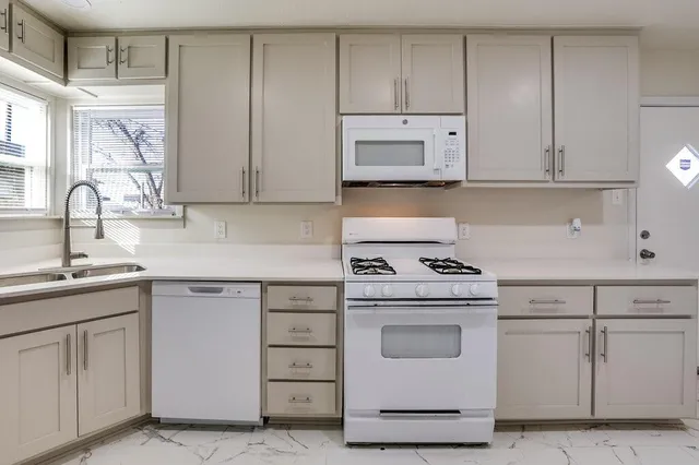 a kitchen with white cabinets and white appliances