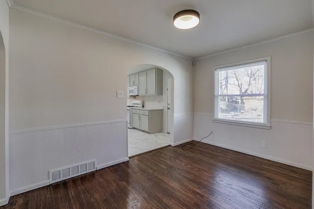 an empty room with wooden floor cabinet and windows