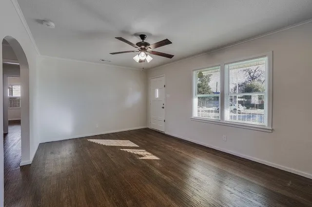 a view of an empty room with wooden floor and a window