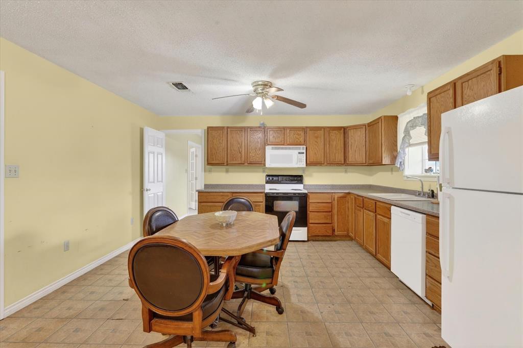 1092 West Highway 199 Springtown, TX 76082 - Photo 11 of 29 Spacious kitchen featuring a ceiling fan, wood-finish cabinetry, and white appliances