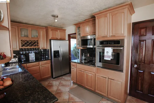 a kitchen with stainless steel appliances granite countertop a refrigerator a stove and a sink