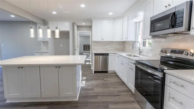 a kitchen with stainless steel appliances kitchen island granite countertop a sink and a stove