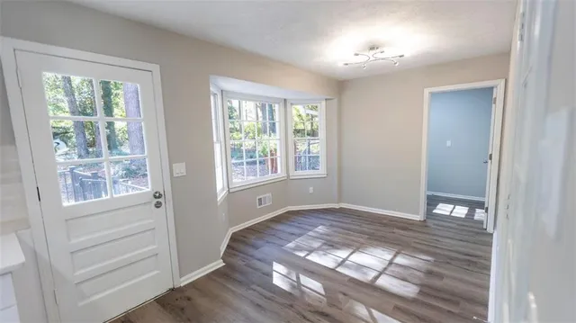 a view of an empty room with a window and wooden floor