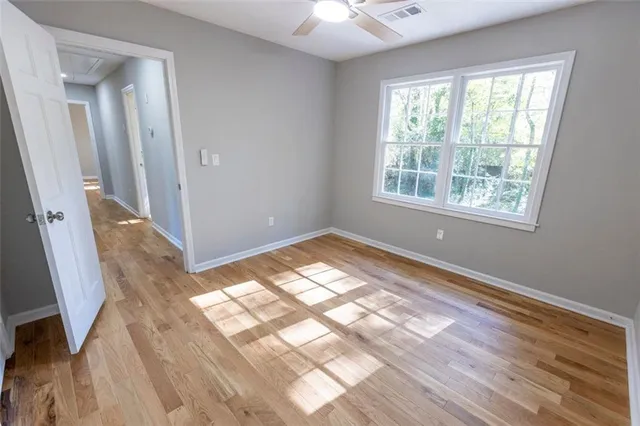 a view of empty room with wooden floor and fan