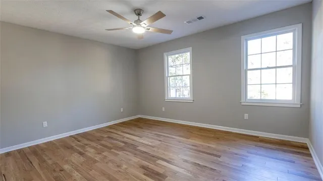 a view of empty room with wooden floor and fan