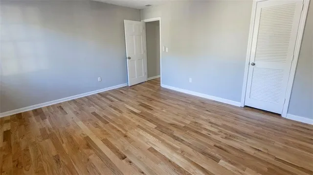 a view of an empty room with wooden floor and closet