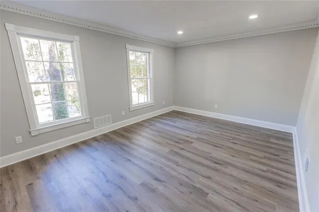 an empty room with wooden floor and windows