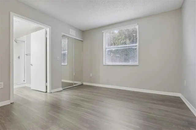 an empty room with wooden floor and windows