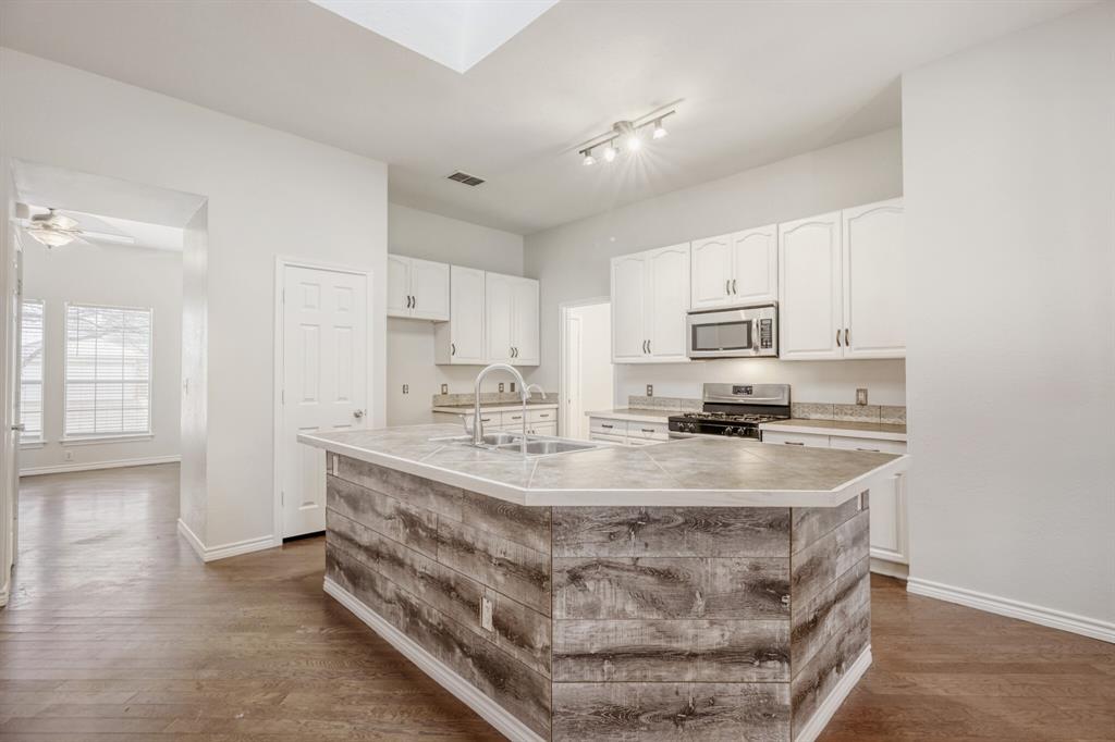 308 Butternut Drive Fate, TX 75087 - Photo 11 of 21 a kitchen with kitchen island granite countertop a sink a counter top space and cabinets