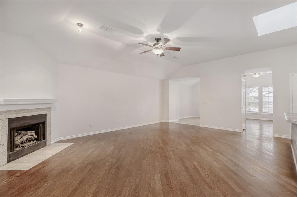 308 Butternut Drive Fate, TX 75087 - Photo 10 of 21 a view of an empty room with wooden floor and a fireplace