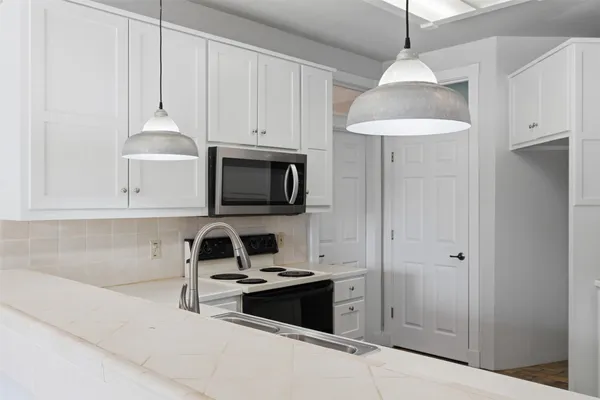 a kitchen with granite countertop white cabinets and a sink