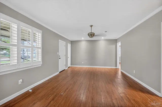a view of an empty room with wooden floor and a window
