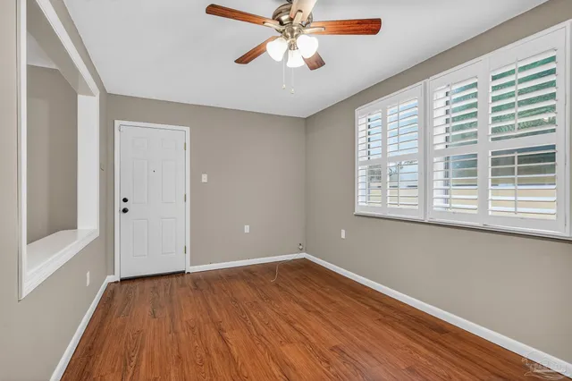 a view of an empty room with window and wooden floor
