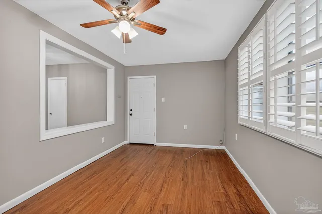 a view of empty room with wooden floor and fan