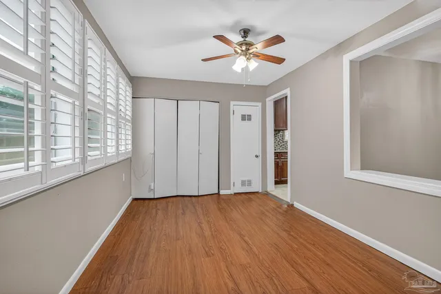 a view of an empty room with wooden floor and a window