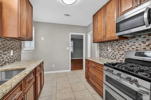 a kitchen with stainless steel appliances granite countertop a stove a sink and a microwave