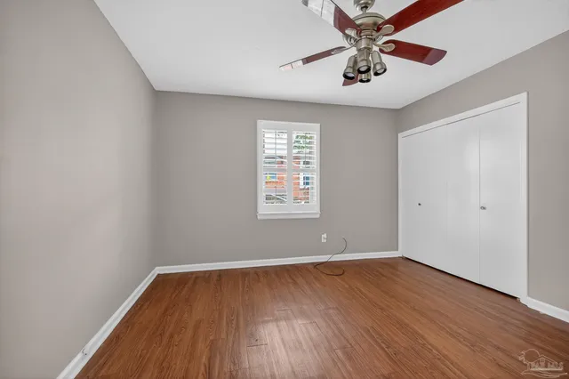 a view of an empty room with window and wooden floor