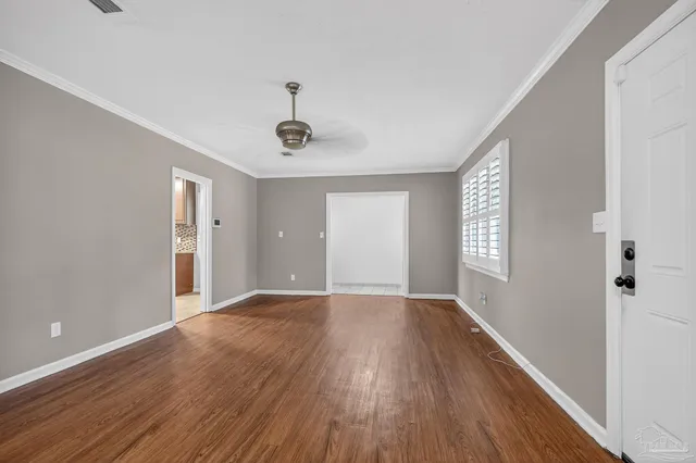 a view of an empty room with wooden floor and a window