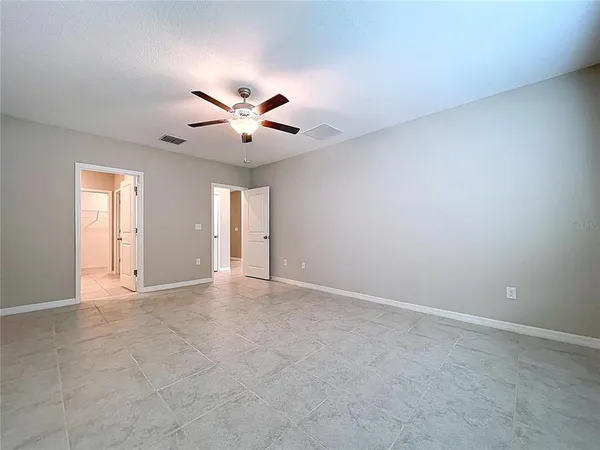 an empty room with wooden floor ceiling fan and windows