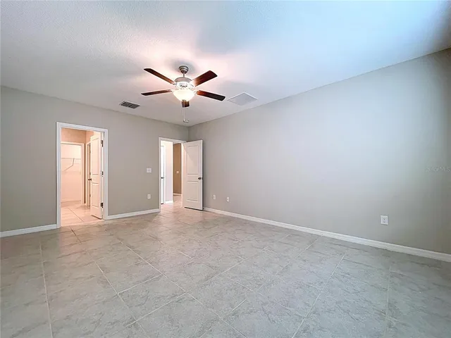an empty room with wooden floor ceiling fan and windows