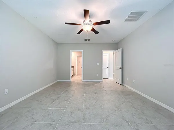 an empty room with wooden floor ceiling fan and windows