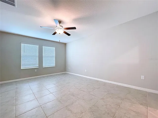 an empty room with wooden floor and a ceiling fan