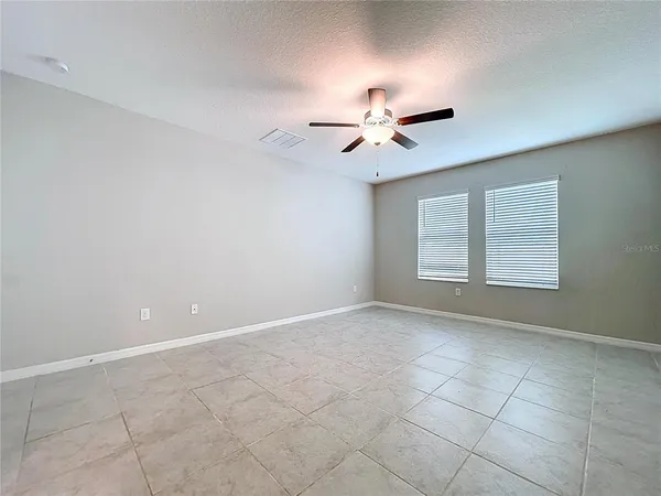 an empty room with wooden floor and a ceiling fan
