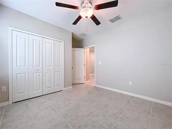 an empty room with wooden floor and ceiling fan