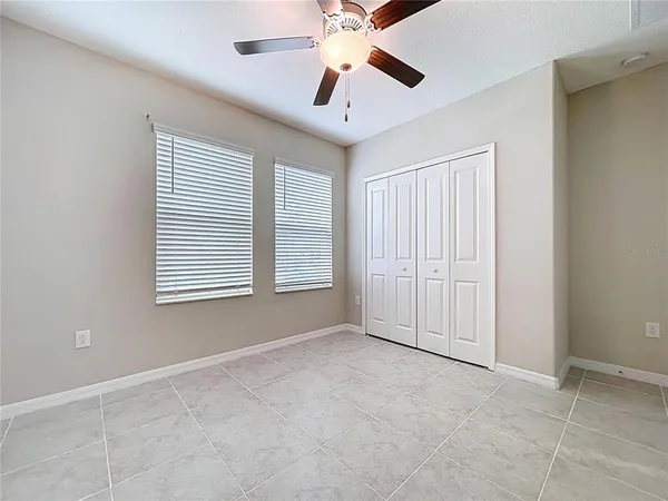 an empty room with wooden floor ceiling fan and windows