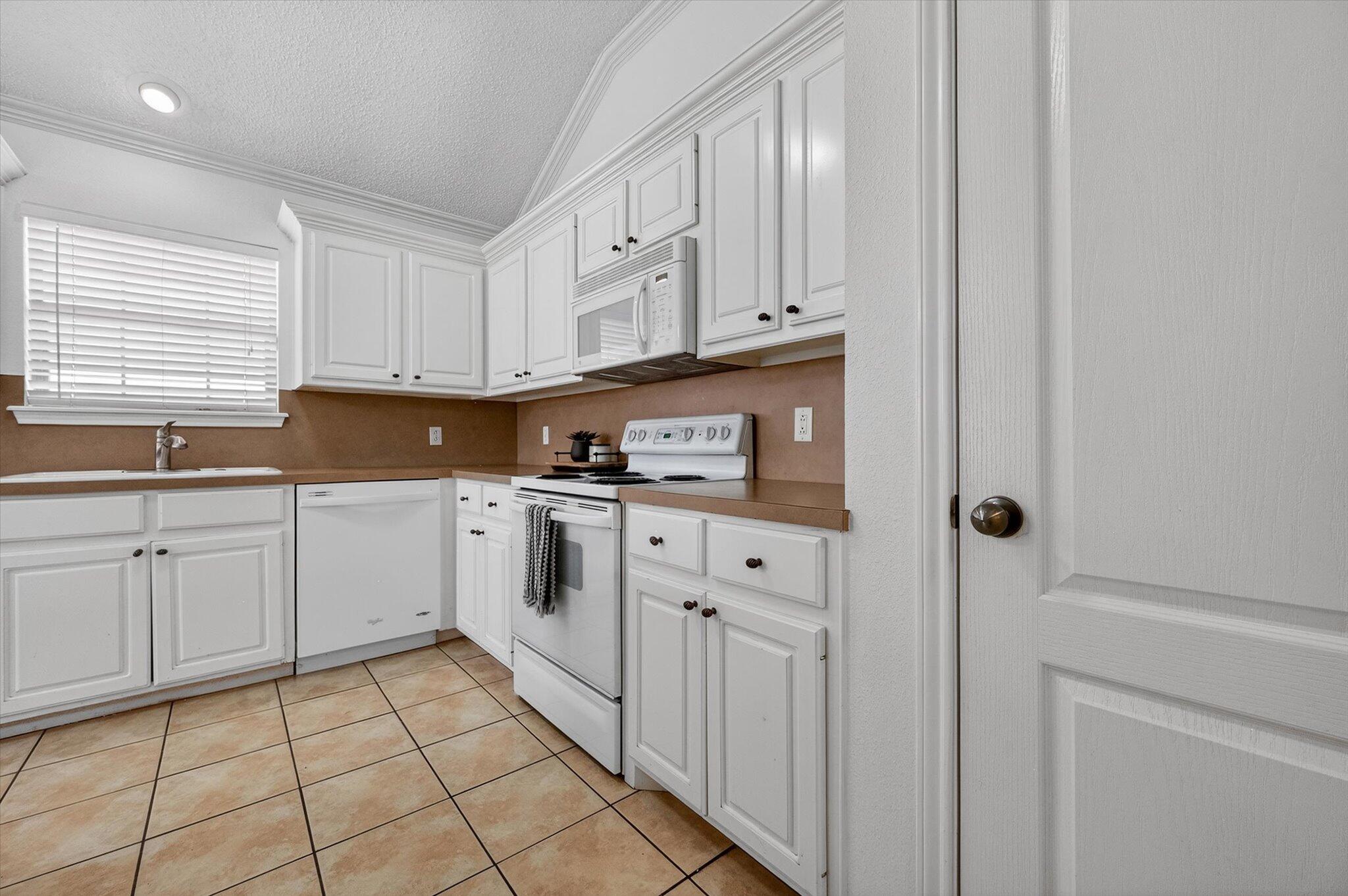 2216 97th Street Lubbock, TX 79423 - Photo 16 of 29 a kitchen with granite countertop white cabinets and white appliances
