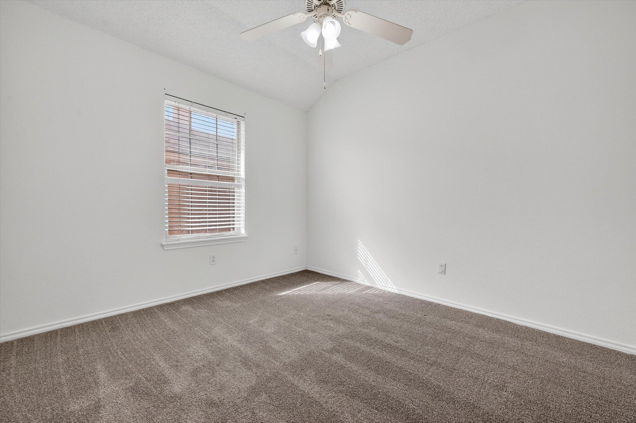 2216 97th Street Lubbock, TX 79423 - Photo 18 of 29 an empty room with a chandelier fan and windows