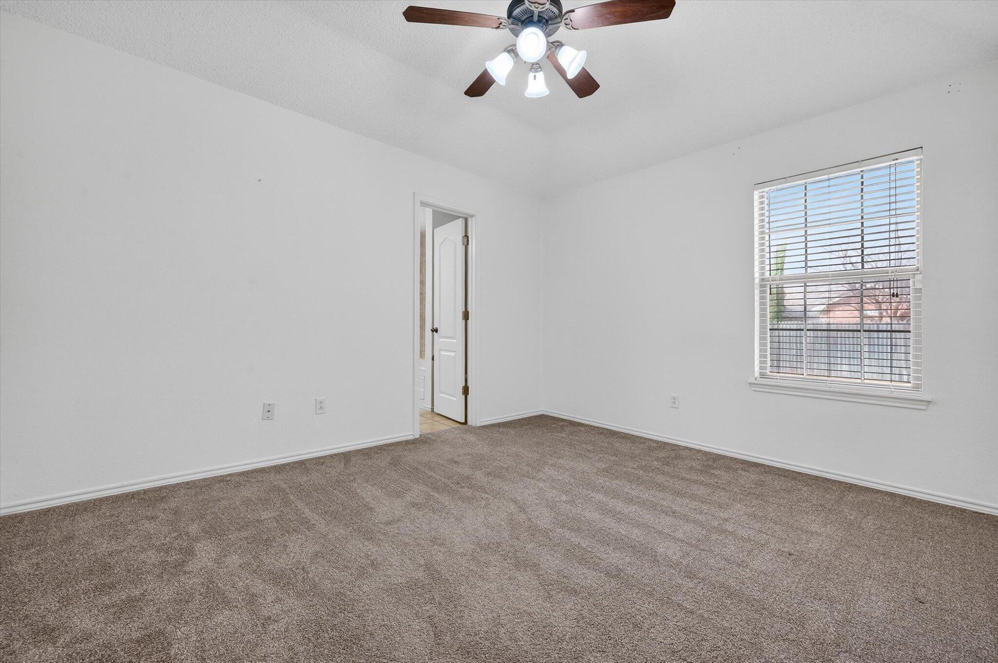 2216 97th Street Lubbock, TX 79423 - Photo 21 of 29 an empty room with a chandelier fan and windows