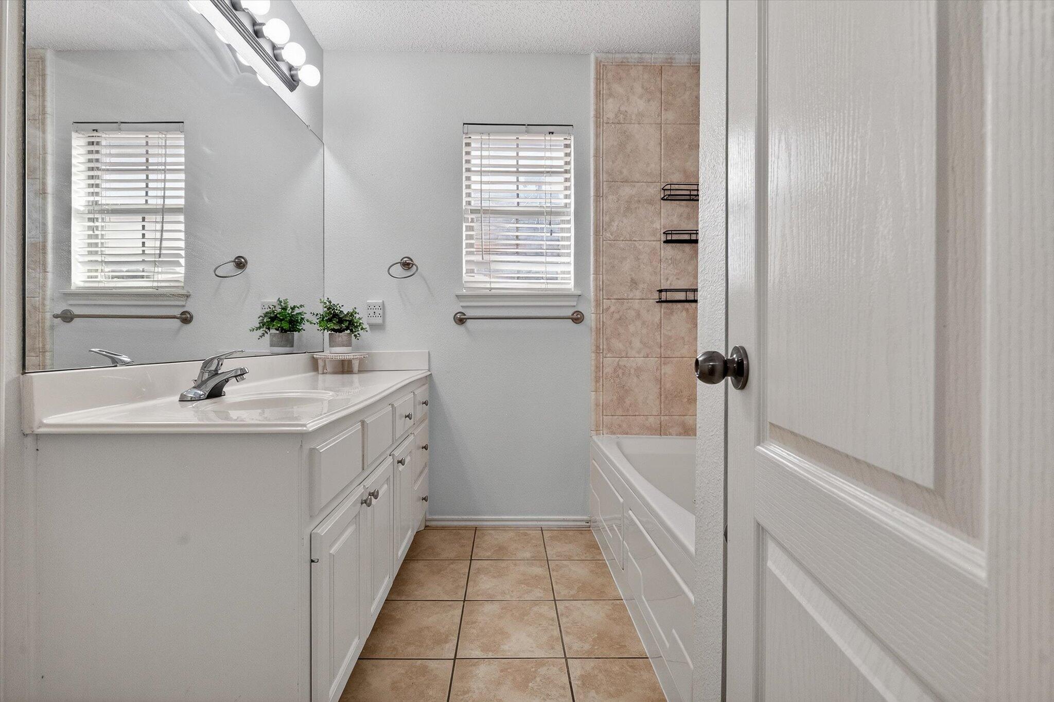 2216 97th Street Lubbock, TX 79423 - Photo 23 of 29 a bathroom with a bathtub sink and mirror