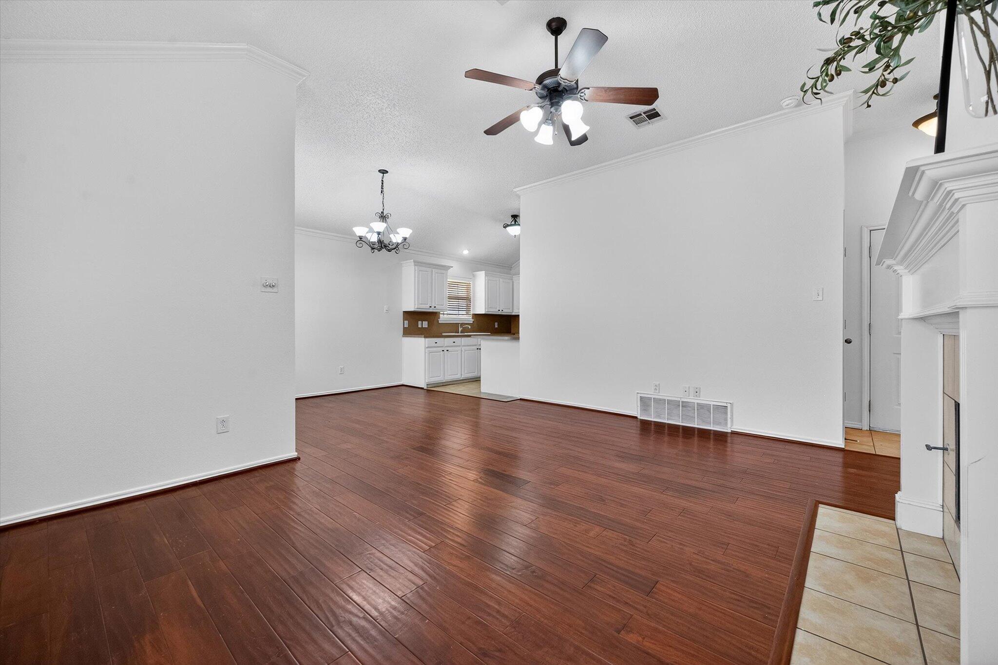 2216 97th Street Lubbock, TX 79423 - Photo 6 of 29 an empty room with wooden floor ceiling fan and kitchen view