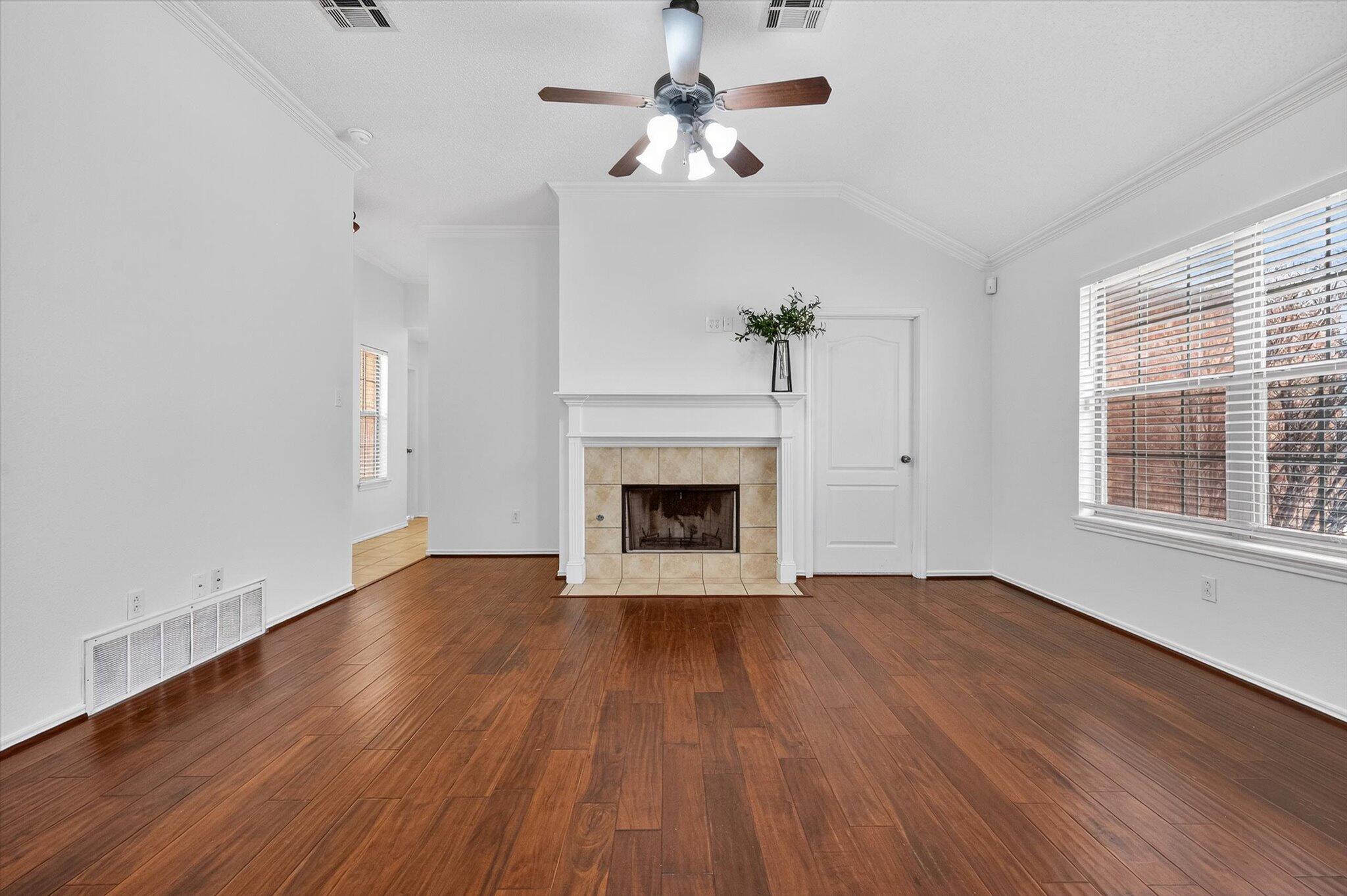 2216 97th Street Lubbock, TX 79423 - Photo 9 of 29 a view of an empty room with wooden floor fireplace and a window