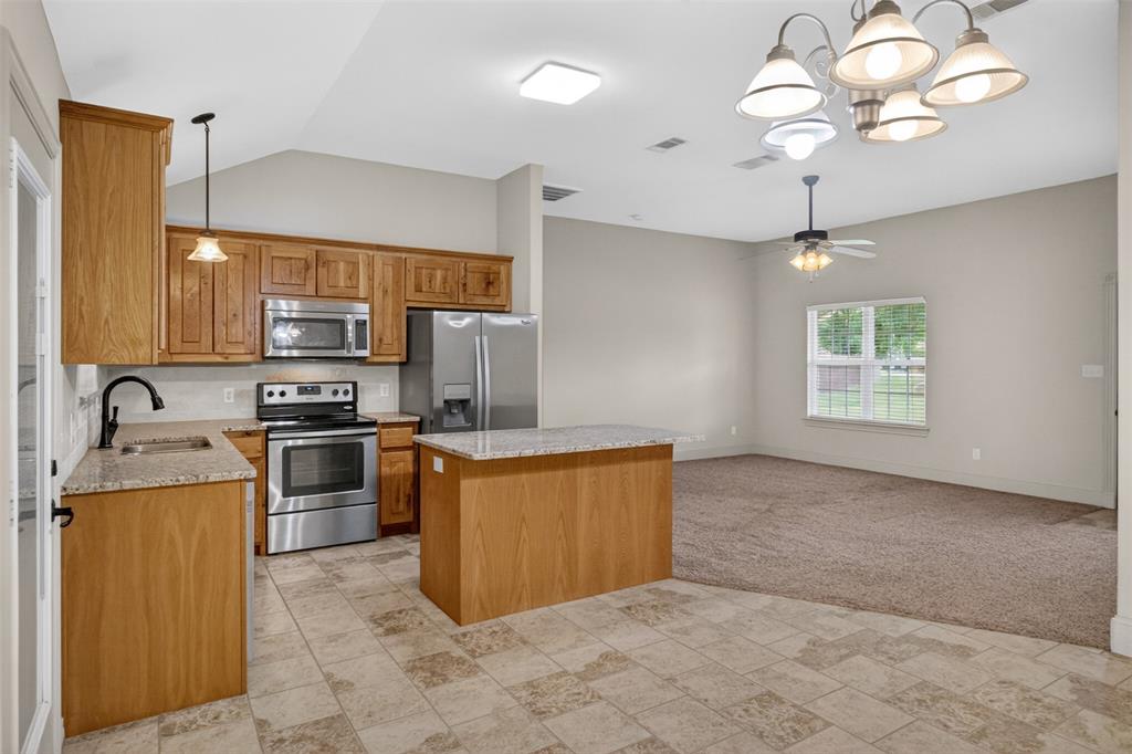 505 East 5th Street Springtown, TX 76082 - Photo 11 of 39 a kitchen with stainless steel appliances granite countertop a sink a stove top oven a counter space and cabinets