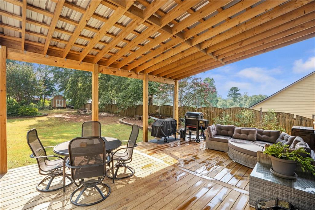 1224 Treemont Trace Winder, GA 30680 - Photo 4 of 27 a view of a patio with couches chairs dining table and chairs barbeque grill with wooden floor and fence
