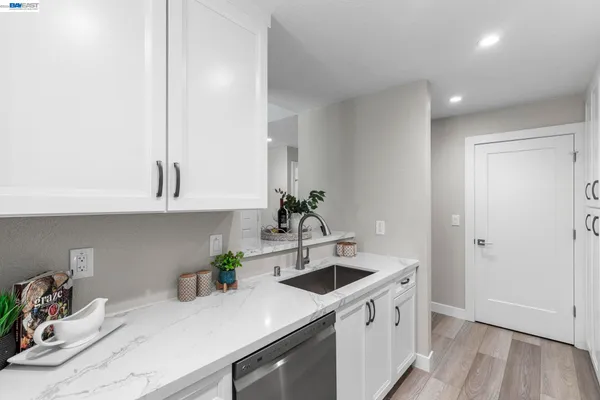 a kitchen with stainless steel appliances white cabinets a sink and wooden floor