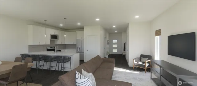 a living room with furniture a flat screen tv and kitchen view