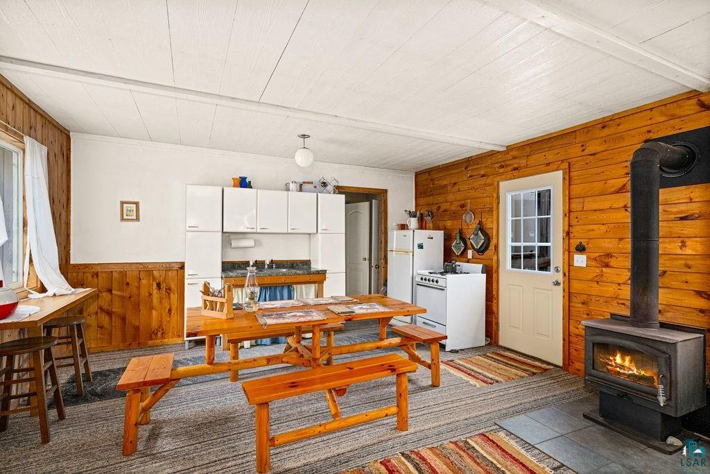 1268 Tom Lake Road Hovland, MN 55606 - Photo 6 of 56 Open-concept living space with wood paneling and a wood-burning stove