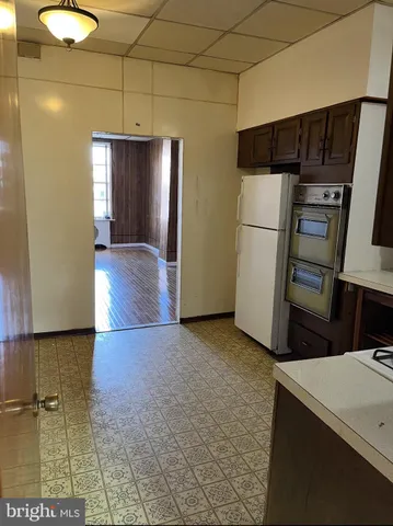 a view of a refrigerator in kitchen and utility room with wooden floor