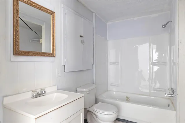 a bathroom with a bathtub shower sink vanity and toilet